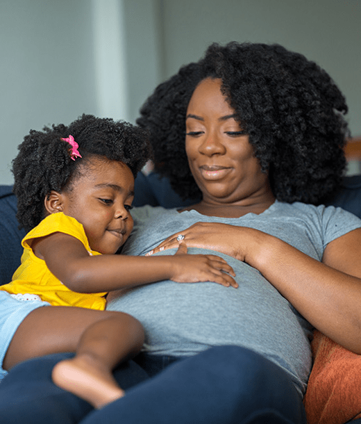 pregnant woman and her young daughter lying on couch