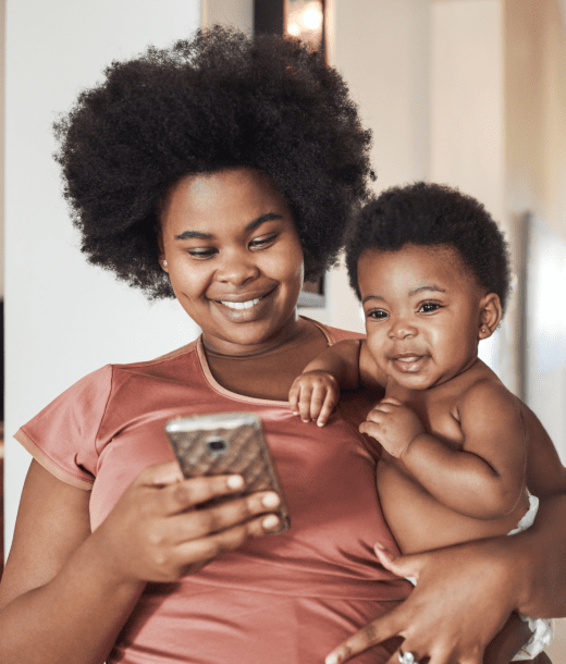 Mother holding baby and looking at cellphone