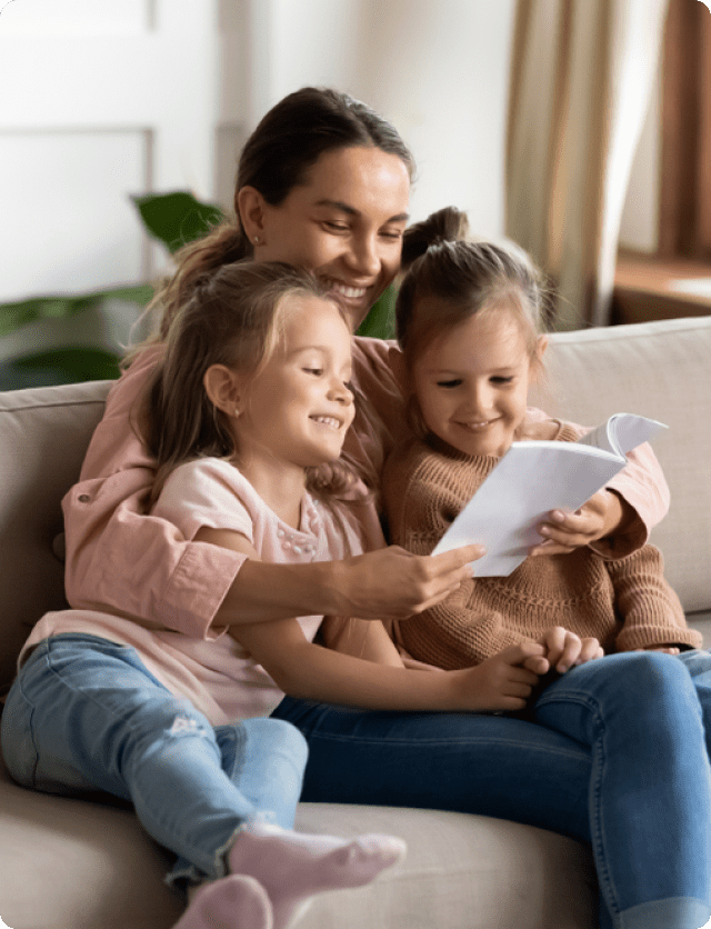 Mother reading a book to two young girls