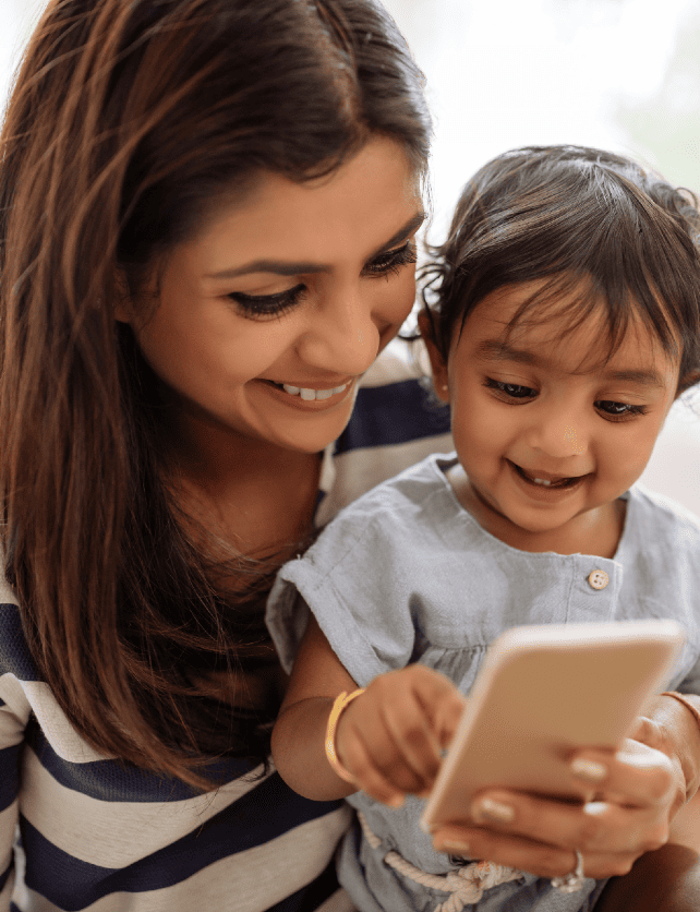 Mother in striped shirt and baby playing with an iPhone and smiling